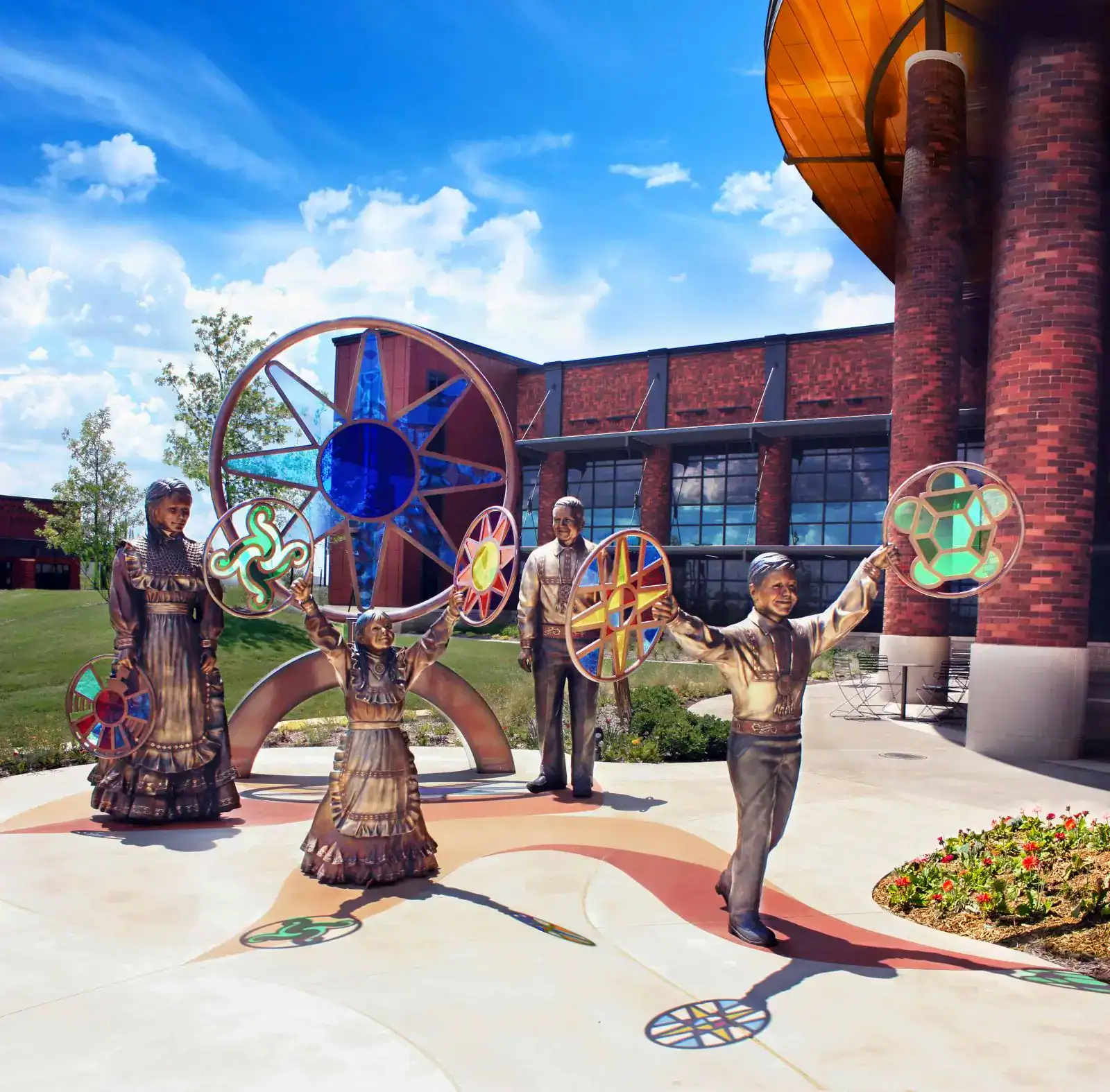 Bronze statues with colorful discs outside building.